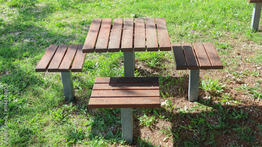 Wooden picnic table with benches on grass in park Wooden picnic table with benches on grass in park