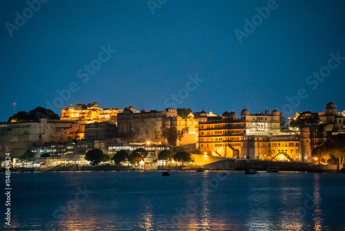 Evening dusk shot of Udaipur city palace on lake pichola lit up with lights reflecting in the water a popular tourist attraction photo