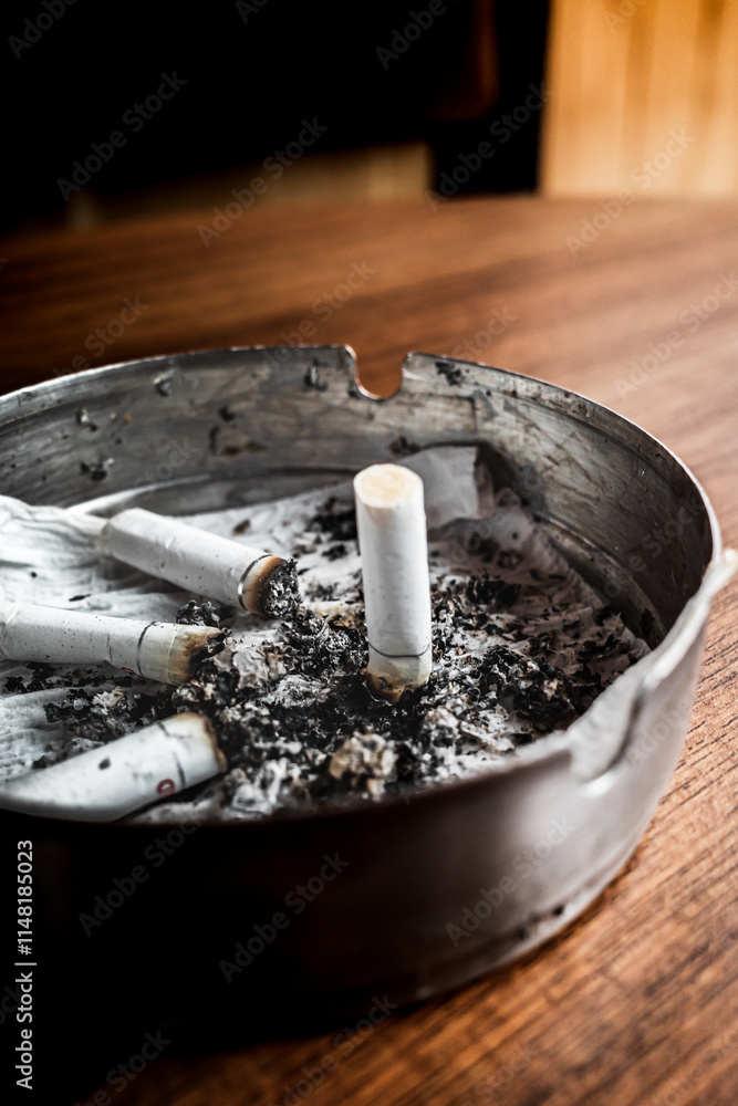 Burnt cigarettes in an ashtray on a wooden table with wet tissue inside Burnt cigarettes in an ashtray on a wooden table with wet tissue inside
