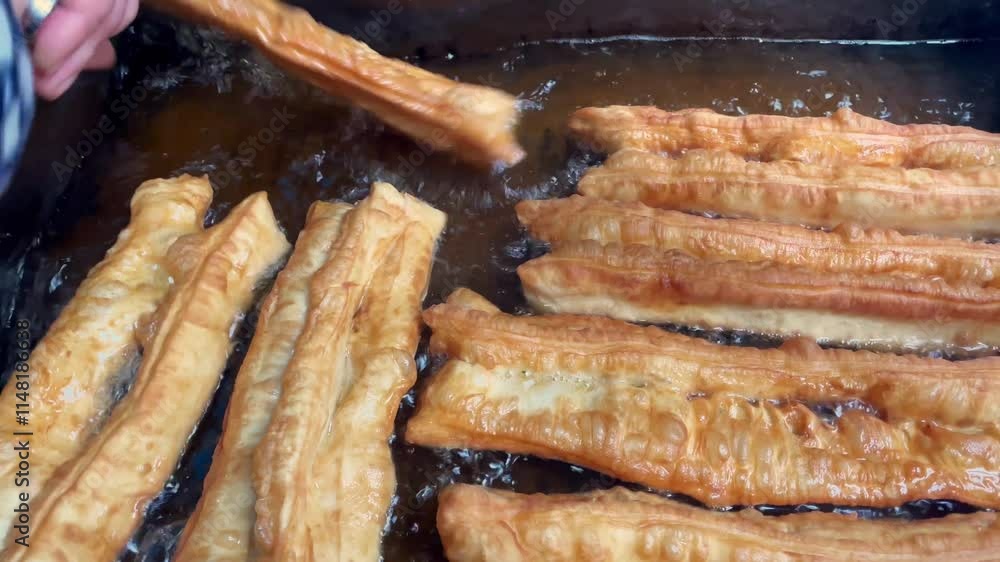 cooking Chinese deep-fried dough stick (also called youtiao). Famous traditional snack in China cooking Chinese deep-fried dough stick (also called youtiao). Famous traditional snack in China