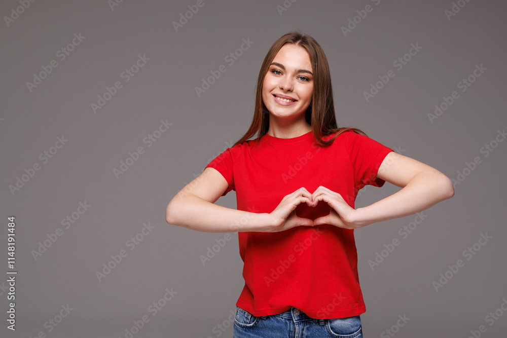Smiling pretty woman showing heart gesture with hands while standing isolated over gray background Smiling pretty woman showing heart gesture with hands while standing isolated over gray background