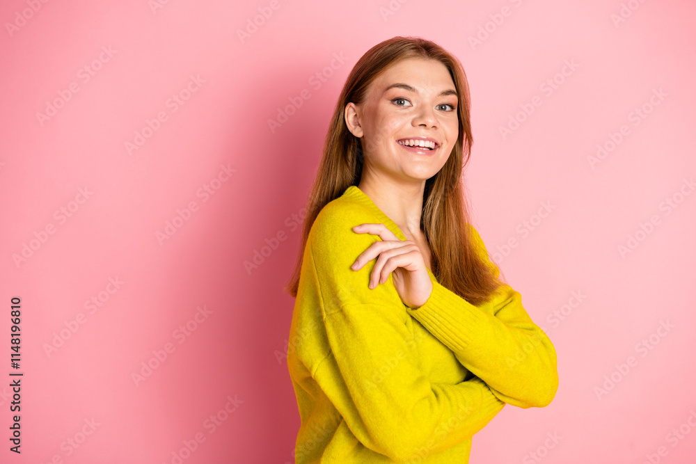 Smiling woman in yellow sweater with arms crossed posing against pink background Smiling woman in yellow sweater with arms crossed posing against pink background