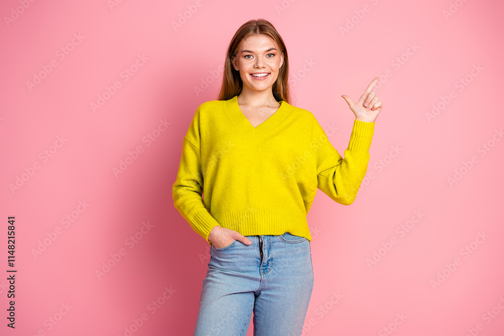Young woman wearing bright yellow sweater pointing with her finger on a pink background Young woman wearing bright yellow sweater pointing with her finger on a pink background