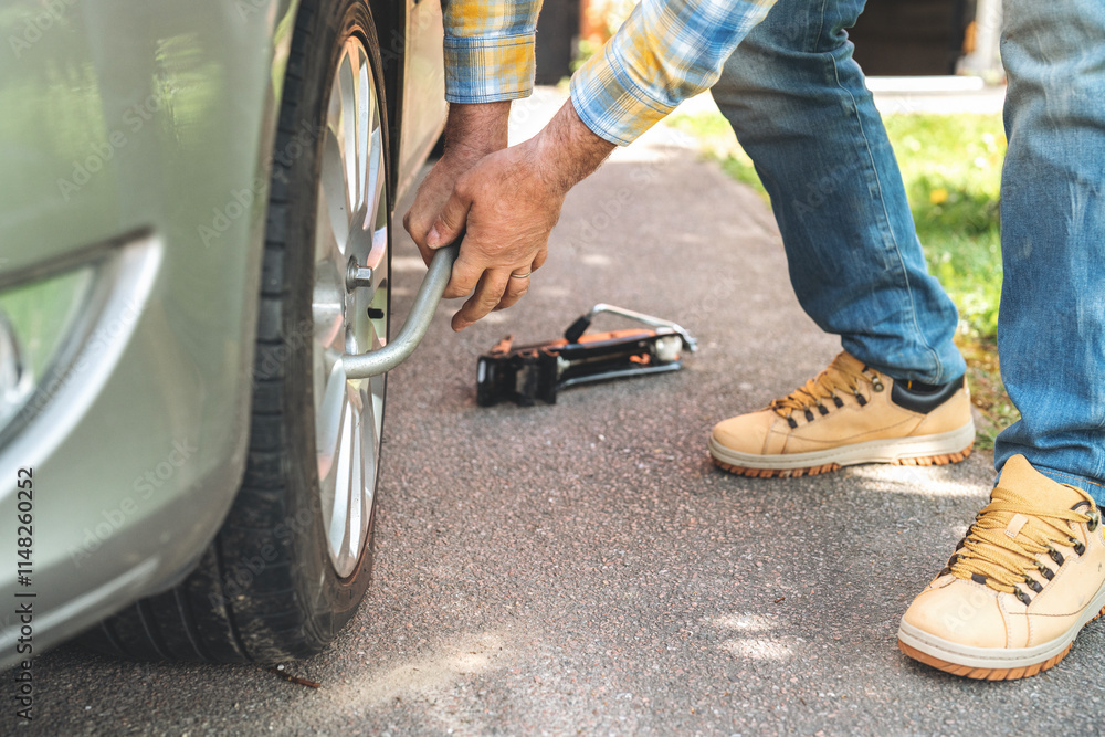 Changing flat tire on sunny day with tools at hand in residential driveway Changing flat tire on sunny day with tools at hand in residential driveway