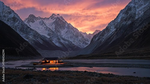 Majestic mountain landscape with a cozy cabin illuminated at sunset in a serene valley