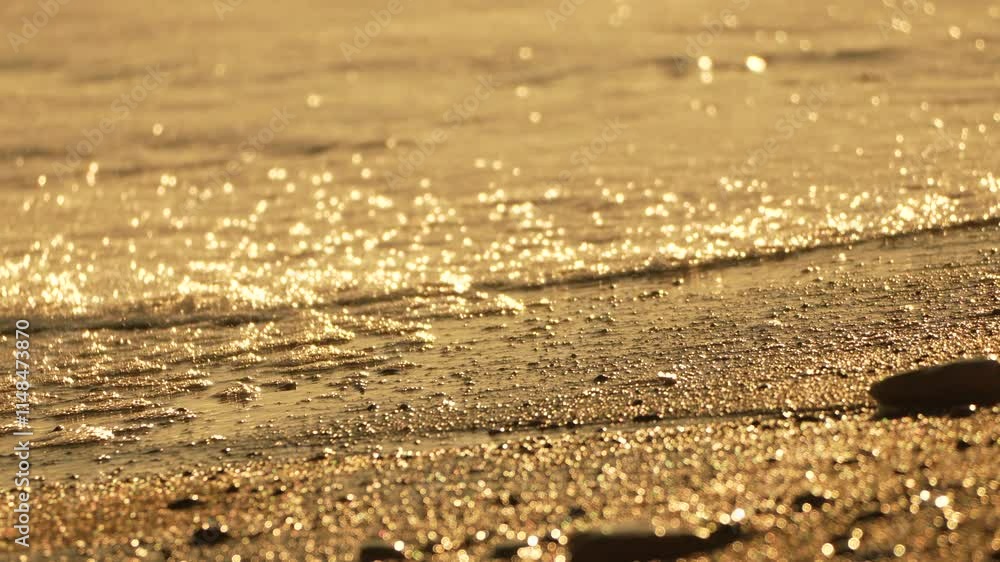 Water, Sand, Sunset: Close-up view of waves lapping onto a sandy beach at sunset. Water, Sand, Sunset: Close-up view of waves lapping onto a sandy beach at sunset.