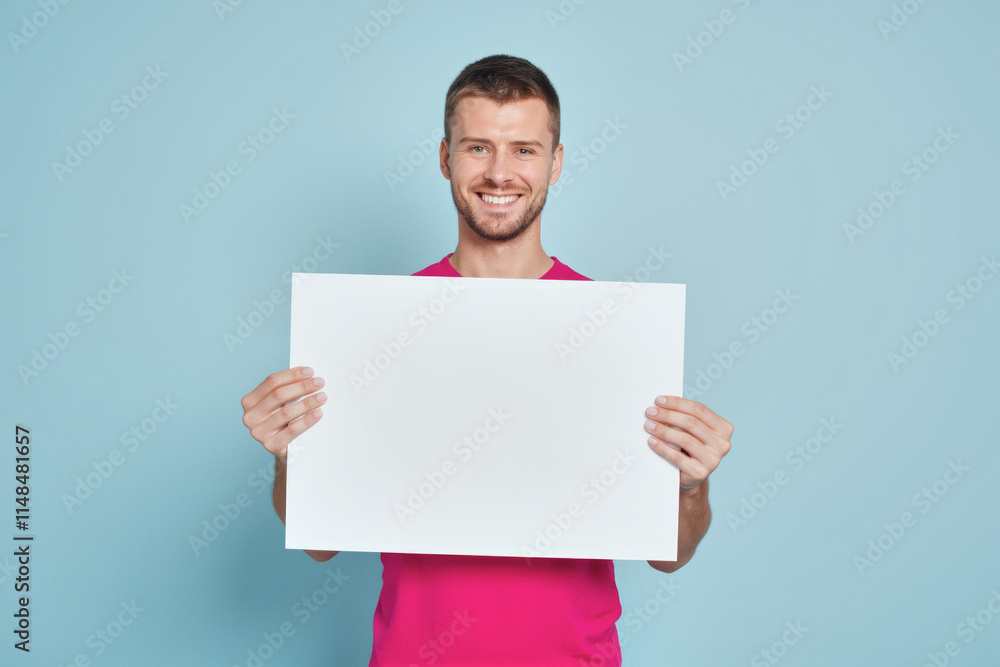 An advertisement studio template portrait photo of a person: a young man with a bright smile on his face, holding a white board in his hands against a blue background. An advertisement studio template portrait photo of a person: a young man with a bright smile on his face, holding a white board in his hands against a blue background.