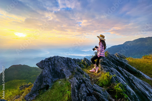 Obraz na plátně Traveller sitting on the rock and holding camera take photo at Doi pha mon mountains in Chiang rai, Thailand