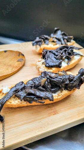 Edible mushroom dead trumpet or autumn trumpet (Craterellus cornucopioides) as a wild mushroom freshly fried on a tasty crispbread with butter