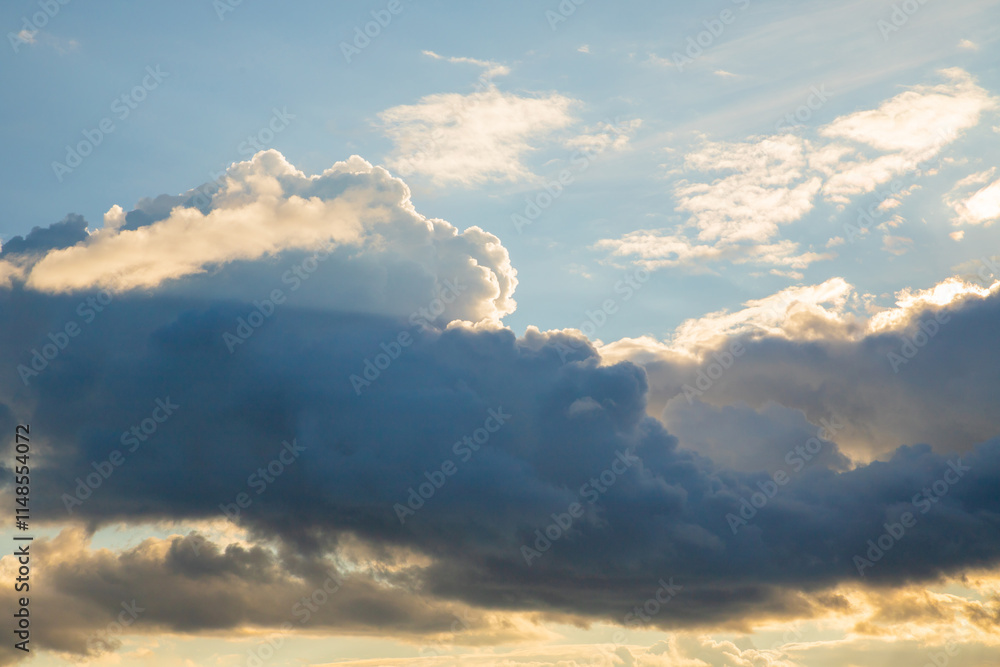 Soft sunlit clouds drift gently across a clear blue sky during the golden hour of late afternoon Soft sunlit clouds drift gently across a clear blue sky during the golden hour of late afternoon