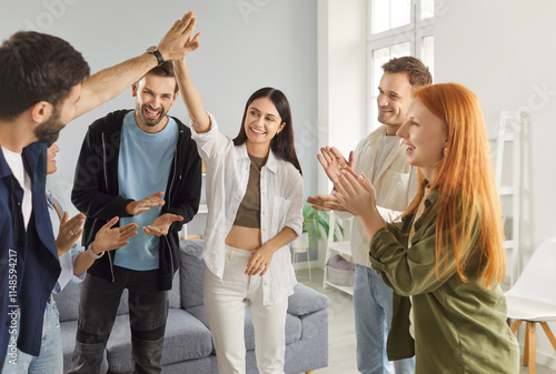 Friends happily give high fives during a party or leisure time at home, celebrating together. Fun and festive atmosphere strengthens friendship, as they enjoy a holiday in a warm and joyful setting. photo