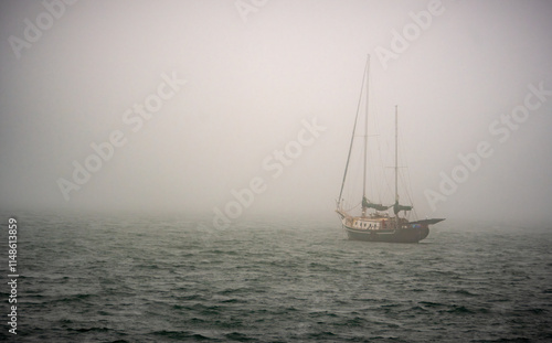Fotografía Misty sea scene: a lone sailboat drifting through dense fog, moody maritime atmosphere and muted horizon conveying solitude and calm adventure