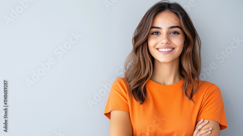 Young caucasian female smiling in orange t-shirt against gray background