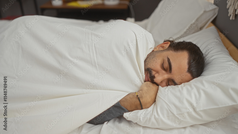 Young hispanic man with a moustache sleeping comfortably in bed in a cozy bedroom at home. Young hispanic man with a moustache sleeping comfortably in bed in a cozy bedroom at home.
