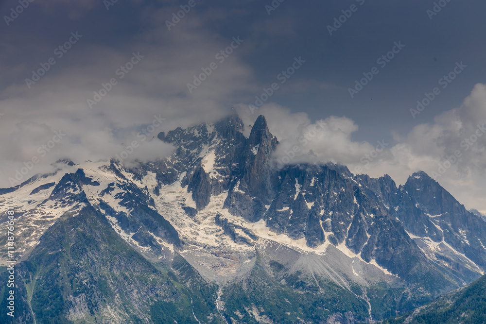 Naklejka premium Nasty weather in the Alps. Dark cloudy sky and overcast before the rain and storm. Stormy weather. Snow and rocky summits of the alpine peaks inside the cloud. Aiguilles du Chamonix in autumn 