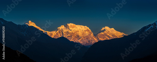 Panoramic view of the snow covered high himalayan mountains after sunset under the colorful blue clean sky. White peaks Manaslu, Himal Chuli and Ngadi Chuli illuminated by the last rays of the sun.