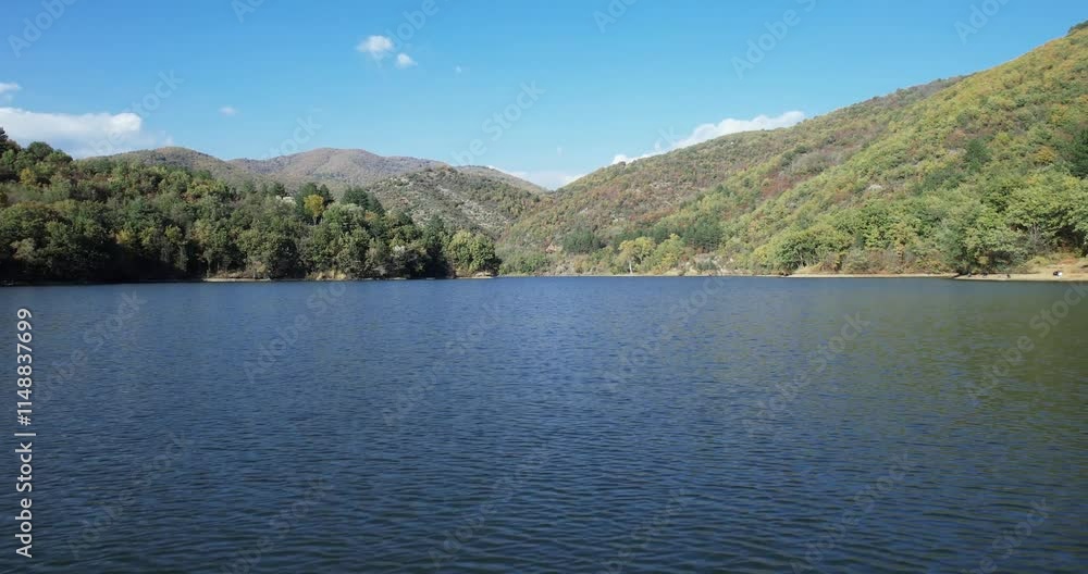 Low angle flight over calm mountain lake water on spring sunny day Low angle flight over calm mountain lake water on spring sunny day