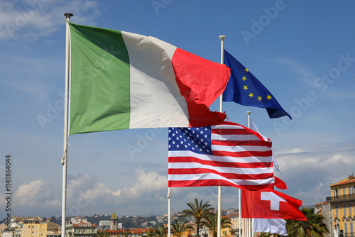 A group of flags can be seen against a blue sky in the city of Nice, France