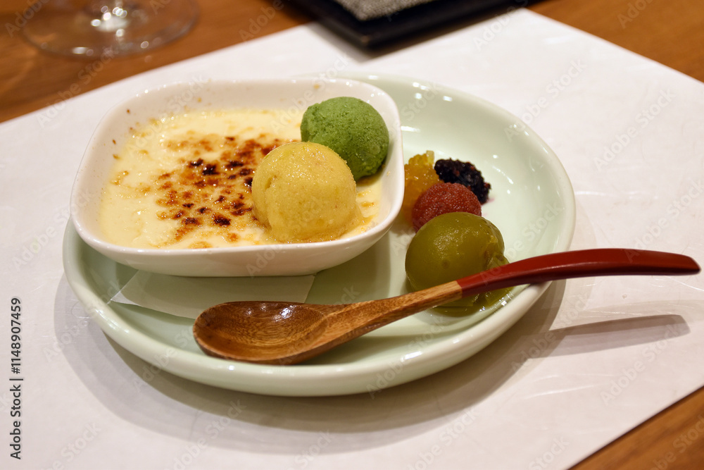 A creamy dessert topped with a caramelized sugar crust, accompanied by colorful scoops of ice cream and small sweet treats, served on a simple plate with a wooden spoon, reflecting Japanese elegance. A creamy dessert topped with a caramelized sugar crust, accompanied by colorful scoops of ice cream and small sweet treats, served on a simple plate with a wooden spoon, reflecting Japanese elegance.