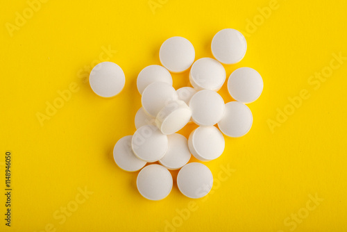 White round pills isolated on a yellow background. A heap of small round meds. Health care and medicine concept