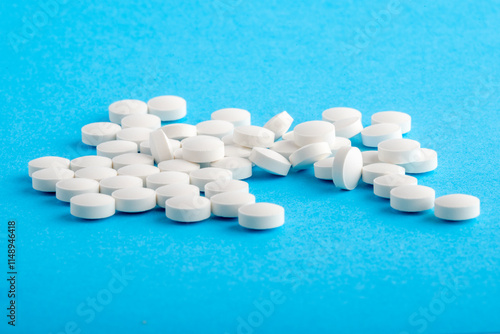 White round pills isolated on a blue background. A heap of small round meds. Health care and medicine concept