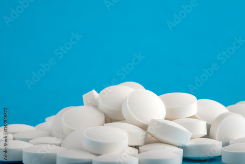 White round pills isolated on a blue background. A heap of small round meds. Health care and medicine concept