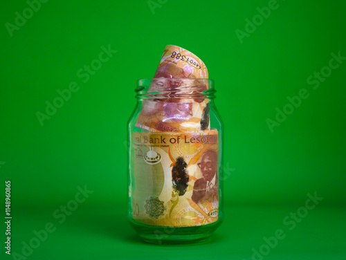 Lesotho Lesothan loti notes in transparent glass jar bottle container isolated green background. savings concept photo