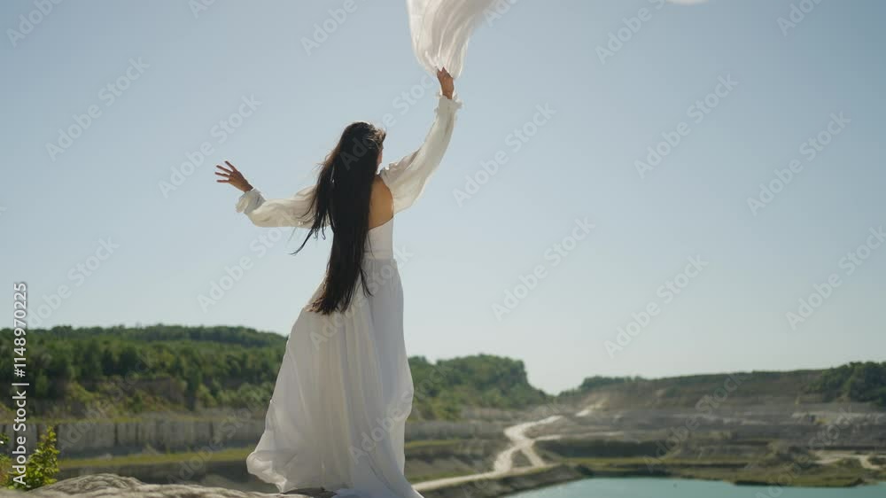 Woman in fluttering white dress stands on rock. Happy bride concept. Woman in fluttering white dress stands on rock. Happy bride concept.