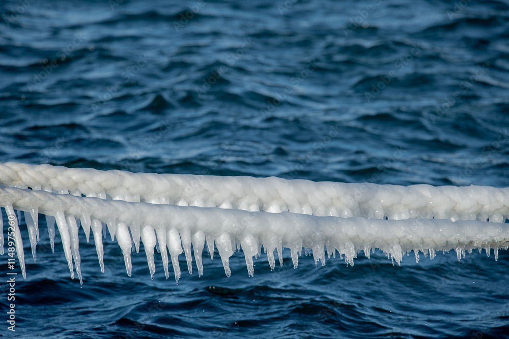 The weather is very cold. Images of frozen ship ropes in the sea. Icicles.