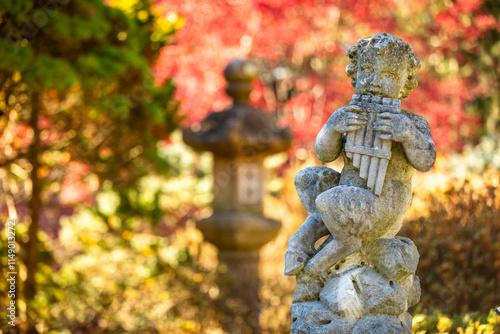 Canvas Print Stone Statue of young Boy (Pan, Faun, Satyr) playing the Pan Flute surrounded by