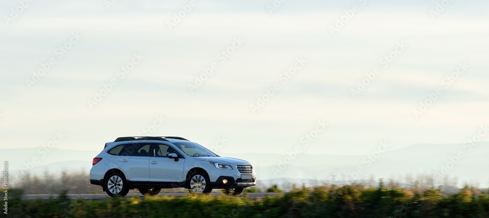 Fototapeta premium SUV car driving fast on intercity road at sunset. Highway traffic in evening