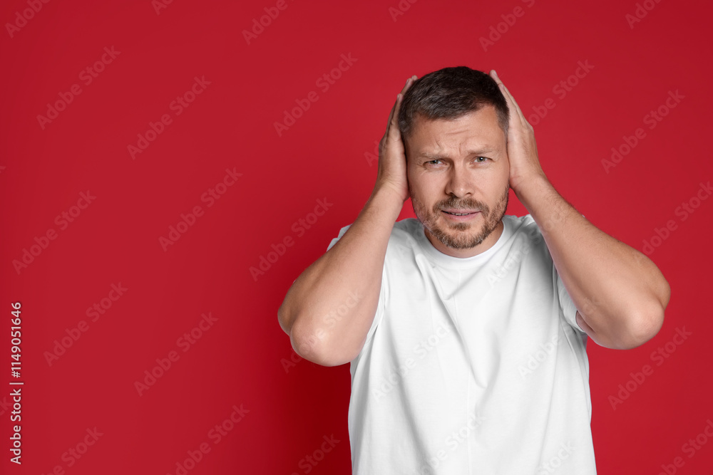 Man covering his ears on red background, space for text