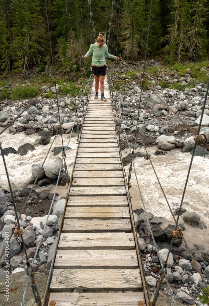 Woman Looks Down Over Rushing Carbon River from Suspension Bridge