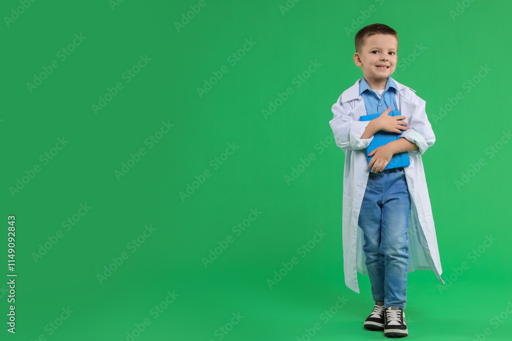 Little boy with book pretending to be doctor on green background, space for text. Dreaming of future profession Little boy with book pretending to be doctor on green background, space for text. Dreaming of future profession