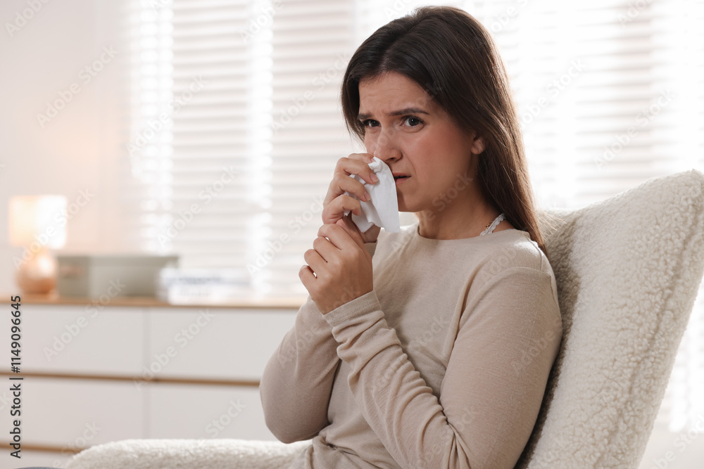 Young woman with tissue blowing runny nose at home. Space for text Young woman with tissue blowing runny nose at home. Space for text