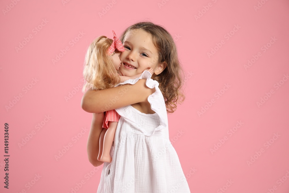 Cute little girl embracing her doll on pink background Cute little girl embracing her doll on pink background