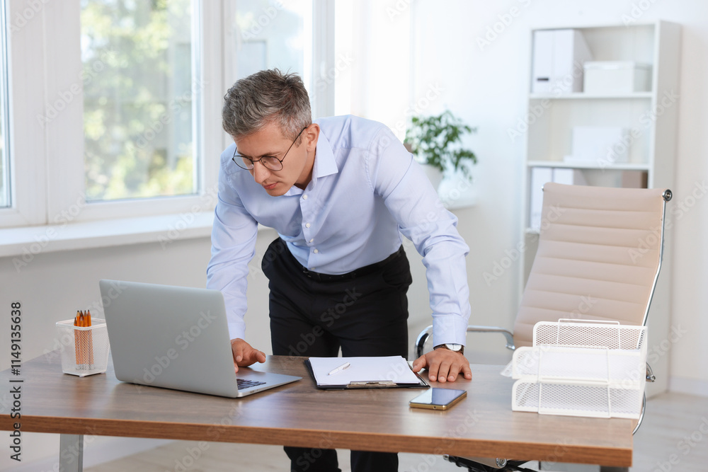 Middle aged man working with laptop in office Middle aged man working with laptop in office