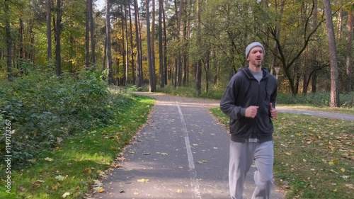 Wallpaper Mural A man jogging in an autumn park. The path is paved, bordered by trees and fallen leaves. He is dressed in casual sportswear Torontodigital.ca