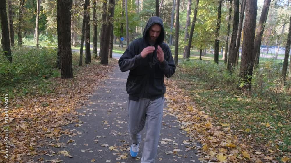 Man in hoodie walks on a fall path in the woods. Man in hoodie walks on a fall path in the woods.