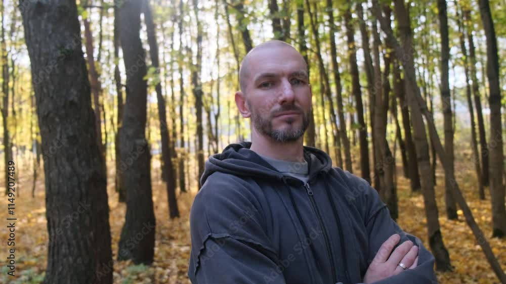 Portrait of a man in hooded jacket in fall woods. Serious look Portrait of a man in hooded jacket in fall woods. Serious look