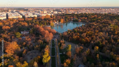 Stunning aerial drone view captures the beauty of El Retiro Park in Madrid, showcasing its vibrant colors and tranquil lake, providing a contrast to the bustling urban landscape of the city