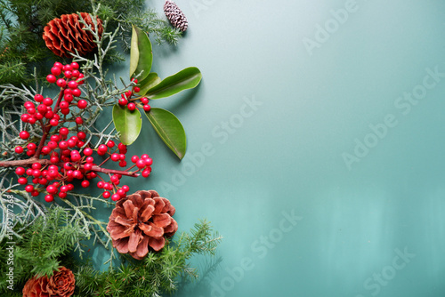 Winter green leaves and berries composition on green background. Winter and Christmas decoration background. Natural elements design for Merry Christmas and Holiday.