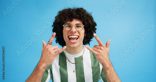 Canvas Print Portrait, rock on and hand gesture with man in studio on blue background with crazy, energy and shout