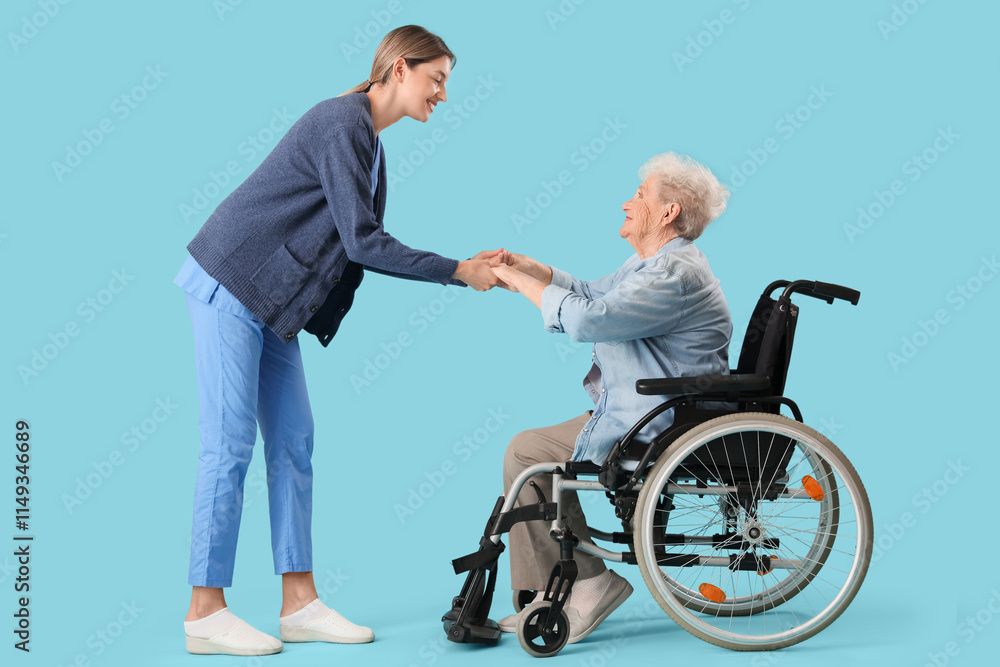 Senior woman in wheelchair with nurse holding hands on blue background Senior woman in wheelchair with nurse holding hands on blue background