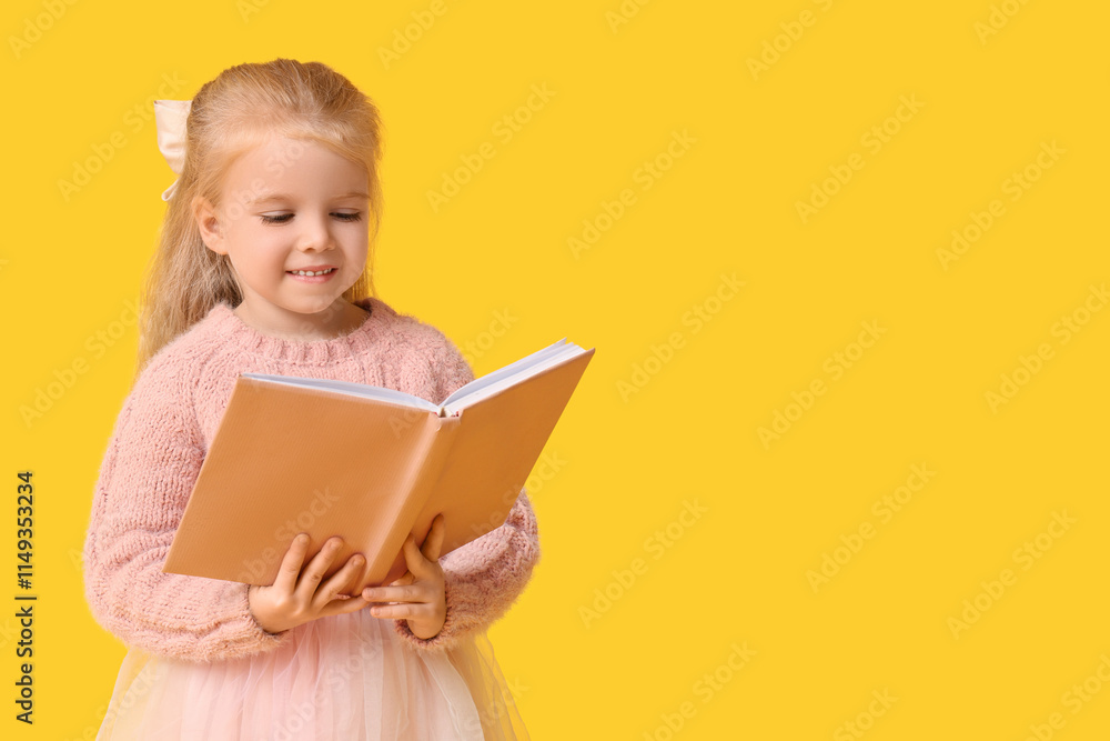 Cute little happy girl in warm stylish sweater reading book on yellow background Cute little happy girl in warm stylish sweater reading book on yellow background