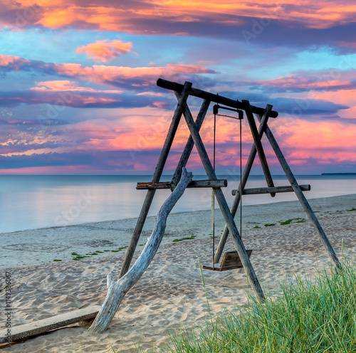 Coastal landscape with wooden swing on sandy beach of the Baltic Sea during c...