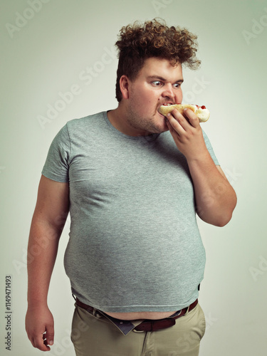 фотографія Studio, plus size and man with hotdog for eating, hungry and bite with expression for takeaway