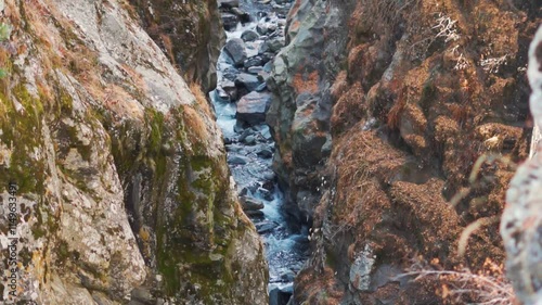 Water stream inside the gorge in the mountain peak as seen from Manali in Himachal Pradesh, India. Water stream flowing in between the space in the mountain. Natural Himalayan stream background. photo