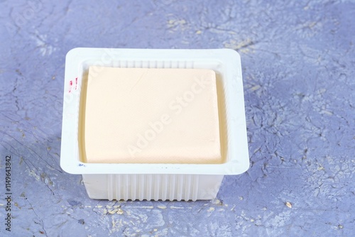 Fresh silken tofu served in a white container on a wooden tray with a garnish of parsley. Perfect for healthy vegan dishes, soups, desserts, or snacks. Smooth texture and rich in nutrients. photo