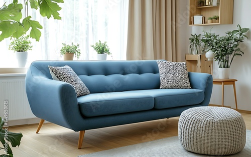 Modern living room interior with blue sofa, plants, and ottoman. photo